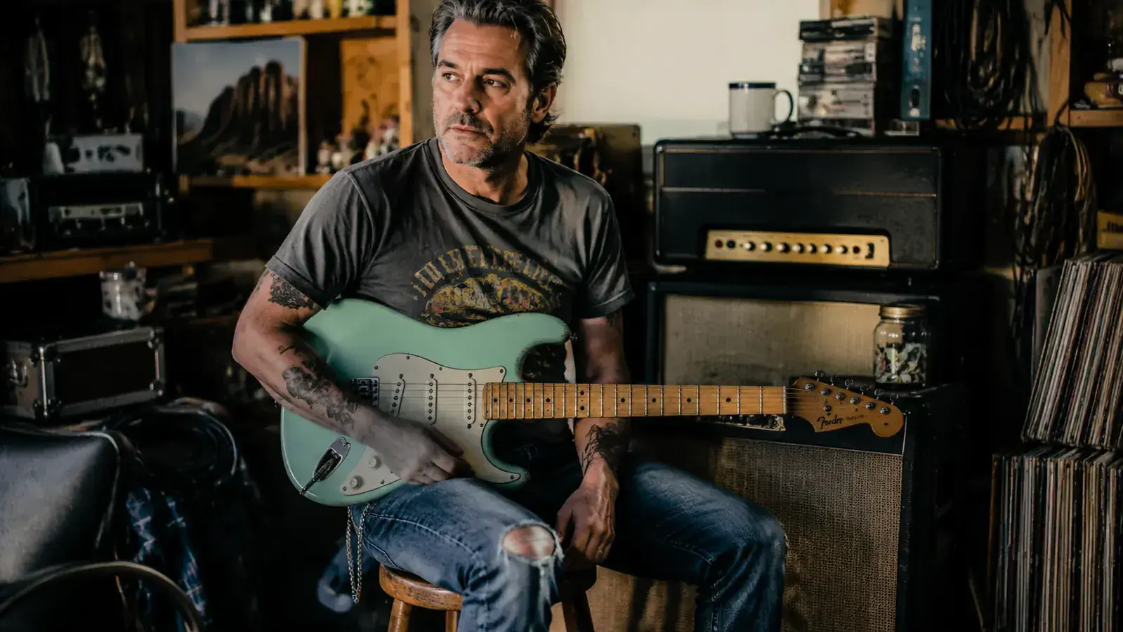 Squier Classic Vibe 50s Stratocaster in Surf Green leaning against a vintage Fender tweed amp in a dimly lit room