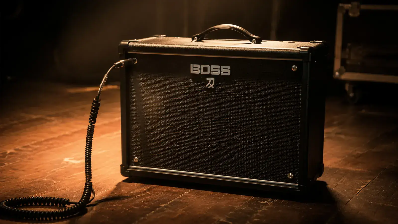 Boss Katana 50 MkII combo amplifier on a wooden stage, warm overhead stage light, gigging environment