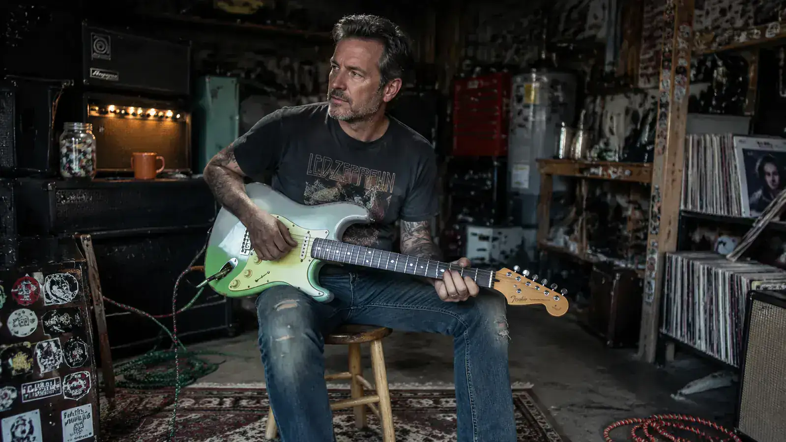 Squier Classic Vibe '50s Stratocaster in Surf Green leaning against a worn Marshall cabinet in a dimly lit rehearsal space